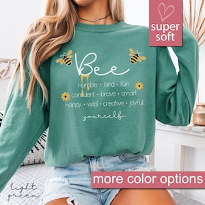 May include: A light green sweatshirt with a bee graphic and the text "Bee yourself" with a list of positive adjectives describing the word "bee".