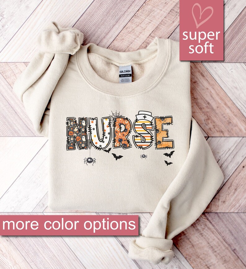May include: A beige sweatshirt with the word "NURSE" in colorful patchwork letters with a Halloween theme. The letters are decorated with spiders, bats, and ghosts. The sweatshirt is super soft.