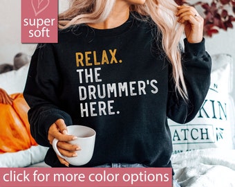 May include: Black sweatshirt with the text "RELAX. THE DRUMMER'S HERE." in white and yellow lettering.