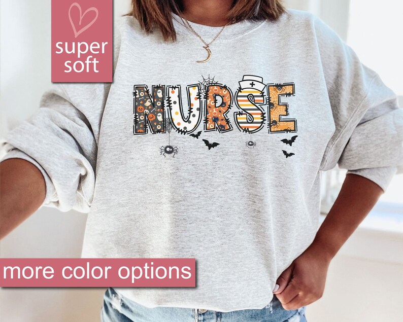 May include: A gray sweatshirt with the word "NURSE" in black, orange, and white letters. The letters are decorated with Halloween-themed patterns, including spiders, bats, and pumpkins.
