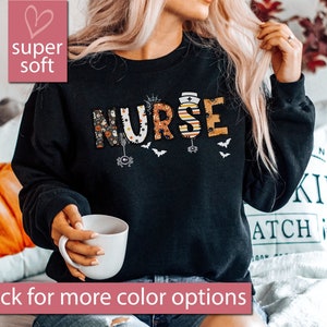 May include: Black sweatshirt with the word "NURSE" in colorful Halloween-themed letters. The letters are decorated with bats, spiders, and other spooky elements.