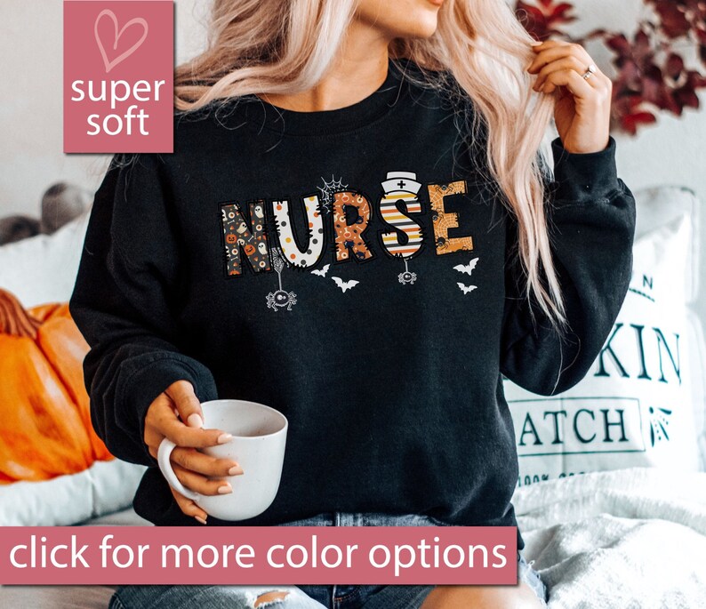 May include: Black sweatshirt with the word "NURSE" in colorful Halloween-themed letters. The letters are decorated with bats, spiders, and other spooky elements.