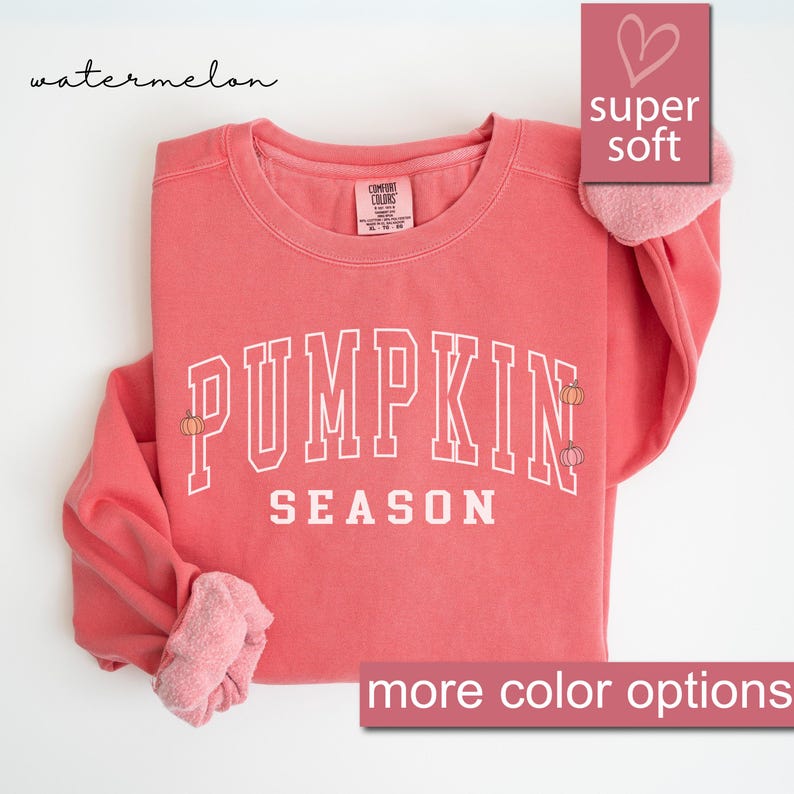 May include: A watermelon-colored sweatshirt with the text "PUMPKIN SEASON" in white with small pumpkin illustrations. The sweatshirt is super soft and comfortable.