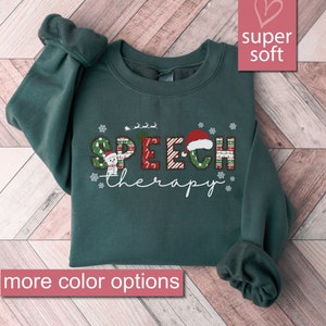 Peut inclure: Un sweat-shirt vert foncé avec les mots "SPEECH therapy" en lettres de Noël festives. Les lettres sont décorées de flocons de neige, d'un bonhomme de neige et d'un chapeau de Père Noël.