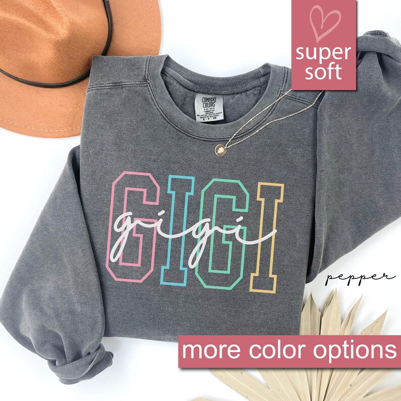 May include: Gray sweatshirt with the word "GIGI" in rainbow colors. The sweatshirt is made of a soft, comfortable material.
