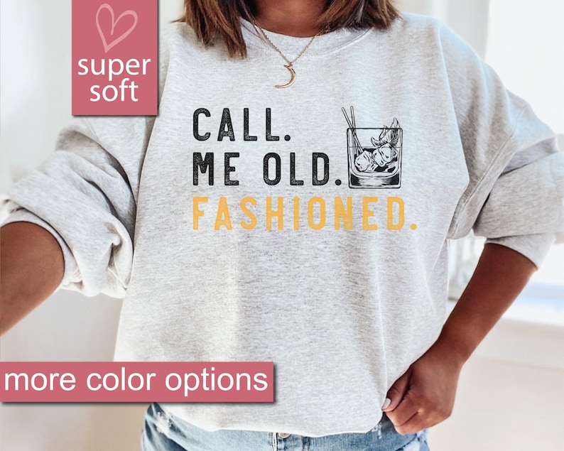 May include: A gray sweatshirt with the text "CALL. ME OLD. FASHIONED." in black and yellow. A black and white illustration of an old fashioned cocktail glass with ice and a cherry is next to the text.