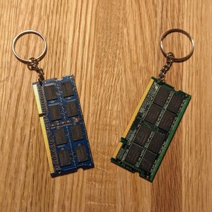 May include: Two keychains made from old computer RAM sticks. One is blue and the other is green.