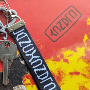 Può includere: Portachiavi nero con testo bianco che dice "2020 NO FUTURE" e un portachiavi argentato con una chiave.