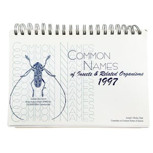 May include: A spiral-bound notebook with the title "COMMON NAMES of Insects & Related Organisms 1997." The cover features a detailed illustration of an insect and the text "COMMON NAMES" in a repeating pattern.