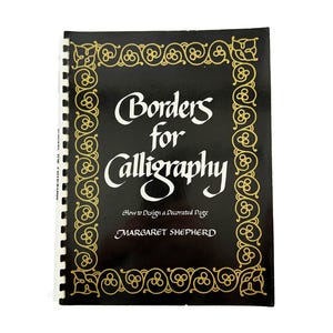 May include: A black book titled "Borders for Calligraphy" with gold decorative borders. The book's cover features white lettering and the author's name, Margaret Shepherd. The book is spiral-bound.