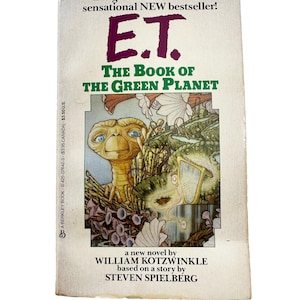 May include: A paperback book cover with a colorful illustration of E.T. the Extra-Terrestrial on a green planet. The title is "E.T. The Book of the Green Planet" and the author is William Kotzwinkle. The book is based on a story by Steven Spielberg.