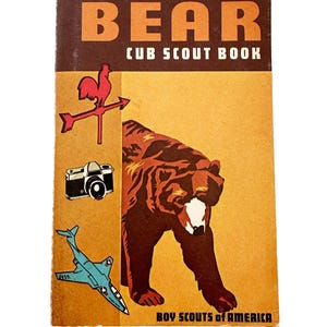 May include: Vintage "Bear Cub Scout Book" cover. The cover features a brown bear illustration, a red rooster weather vane, a camera, and a blue jet. The text "BEAR CUB SCOUT BOOK" and "BOY SCOUTS OF AMERICA" are also visible.