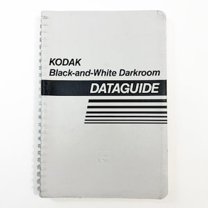 Puede incluir: Un DATAGUIDE KODAK de cuarto oscuro en blanco y negro con espiral. La portada es de color gris claro con texto negro y una franja horizontal negra con líneas paralelas. El logotipo de KODAK es visible.