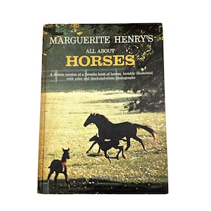 Puede incluir: Un libro antiguo titulado "Marguerite Henry's All About Horses". La portada presenta siluetas de caballos corriendo en un campo. El libro es una edición de lujo con fotografías en color y en blanco y negro.