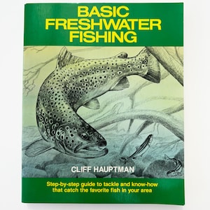 May include: A book titled "BASIC FRESHWATER FISHING" with a green and yellow cover. The cover features an illustration of a fish and the author's name, Cliff Hauptman. The book's subtitle is "Step-by-step guide to tackle and know-how that catch the favorite fish in your area."