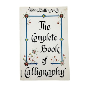 May include: A vintage book titled "The Complete Book of Calligraphy" by Emma Macalik Butterworth. The cover is white with a blue border and decorative floral accents. The title is in elegant black calligraphy.