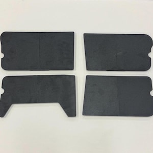 May include: Four flat, matte black rectangular components with rounded corners and small semi-circular cutouts along the edges. Three of the pieces are solid rectangles, while one piece features a distinct angular cutout on the bottom left side.