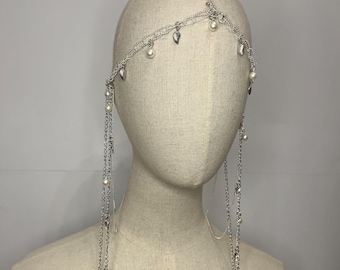 May include: A silver headpiece with multiple chains and pearl accents. The chains are connected to small silver leaves and dangle down with more pearls.
