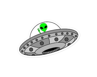 May include: A green alien with a peace sign hand gesture is flying in a gray and black UFO.