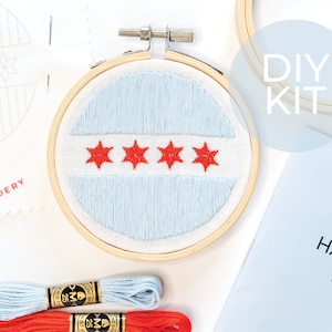 May include: DIY embroidery kit featuring a blue and red Chicago flag design. The kit includes a hoop, embroidery floss, and instructions.