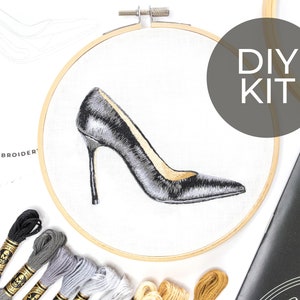 May include: DIY embroidery kit featuring a black high heel shoe design. The kit includes embroidery floss in black, gray, and beige colors, a hoop, and instructions.
