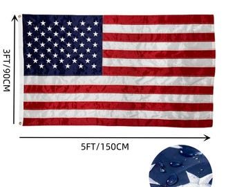以下が含まれることがあります： 耐候性のある生地で作られた、90cm x 150cmのアメリカ国旗。旗は赤、白、青で、青いフィールドに50個の星があります。旗は水滴がついた状態で表示されており、耐水性を示しています。