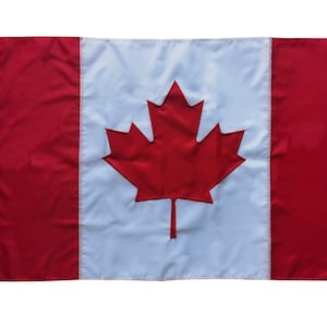 May include: A Canadian flag with a red maple leaf on a white background and red stripes on the sides.