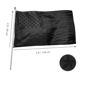 May include: A black American flag measuring 150 cm wide and 90 cm high. The flag is made from a shiny, textured material. The flag is displayed on a silver pole with a gold finial.