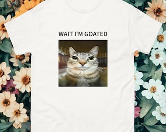 May include: White t-shirt with the text "WAIT I'M GOATED" and a picture of a tabby cat with green eyes.