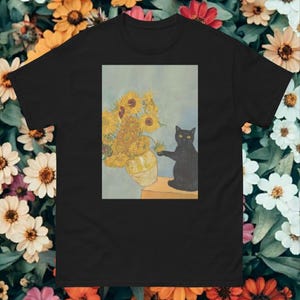 Könnte beinhalten: Schwarzes T-Shirt mit einem Gemälde von Sonnenblumen in einer Vase und einer schwarzen Katze. Die Katze greift nach einer Sonnenblume. Das Kunstwerk ist vor einem hellblauen Hintergrund platziert. Das Shirt besteht aus einem weichen, bequemen Material.