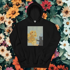 Könnte beinhalten: Schwarzer Kapuzenpullover mit einem Aufdruck von Sonnenblumen in einer Vase und einer schwarzen Katze, im Stil von Van Gogh. Der Pullover hat eine Vordertasche und eine Kapuze mit Kordelzug.