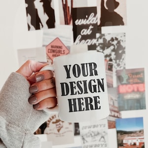 May include: White ceramic mug with the text "YOUR DESIGN HERE" in bold black letters. The mug is held in front of a collection of Western-themed images, including silhouettes of cowgirls and cacti.