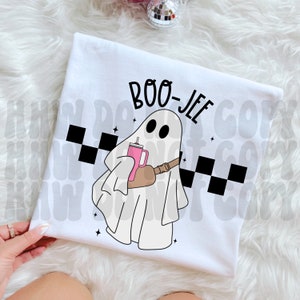 May include: White t-shirt featuring a ghost wearing a brown crossbody bag and holding a pink drink. The text "BOO-JEE" is above the ghost.