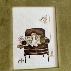 May include: A watercolor illustration featuring a brown and white beagle sitting on a dark brown armchair. The scene includes a small side table with pink flowers, a patterned throw pillow, and a tall floor lamp with a grid-patterned shade.