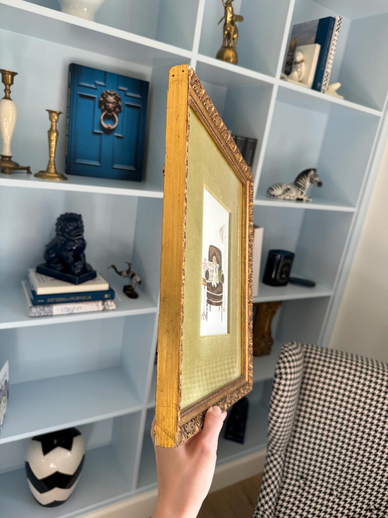 May include: A rectangular picture frame with an ornate gold finish and a textured green matting. The frame contains a small illustration of a brown armchair with a white dog sitting on it, accompanied by the text "BE KIND TO YOURSELF".