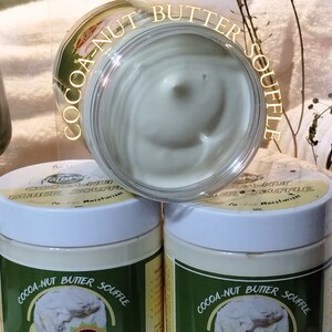 May include: Three jars of cocoa-nut butter souffle moisturizer. The jars are white with green labels and gold lettering. The label reads "Cocoa-Nut Butter Souffle".