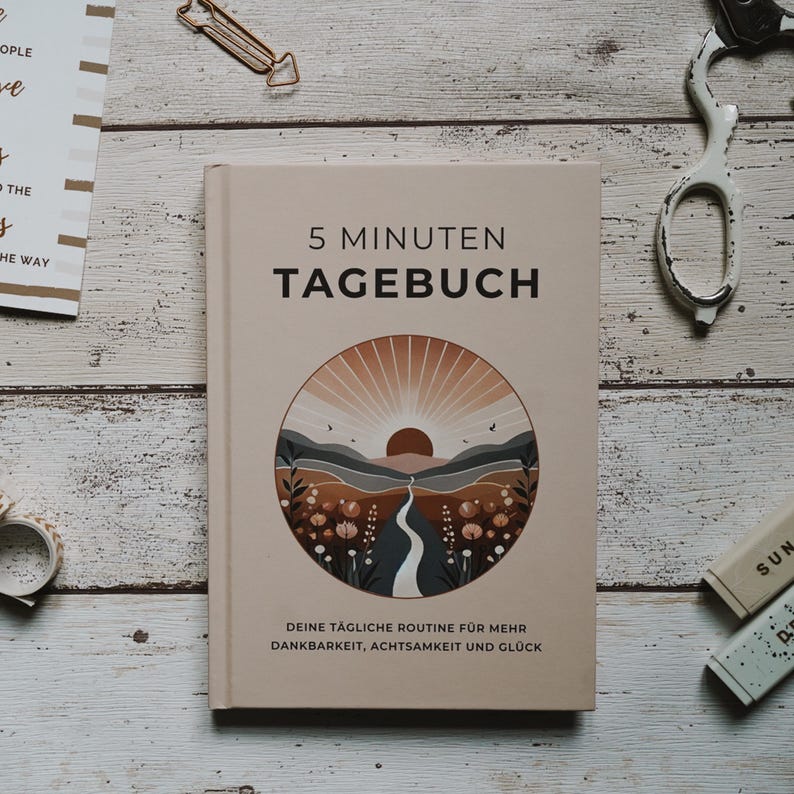 May include: A beige journal with the title "5 Minuten Tagebuch" and a sunset landscape illustration. The text below the illustration reads "Deine t&auml;gliche Routine f&uuml;r mehr Dankbarkeit, Achtsamkeit und Gl&uuml;ck".