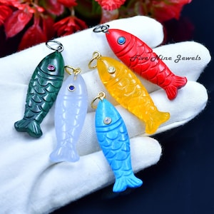 May include: Five colorful fish pendants with gemstone eyes. The fish are carved from jade, turquoise, and other materials.  The pendants are perfect for jewelry making or adding a touch of whimsy to your home decor.