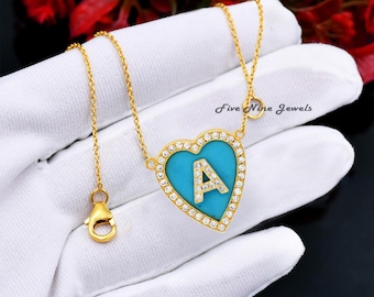 May include: Gold heart-shaped pendant necklace with a turquoise blue center and a clear crystal border. The pendant features a gold letter 'A' in the center. The necklace has a gold chain and a lobster clasp.