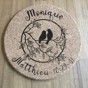 Peut inclure: Un dessous de plat rond en liège avec un motif noir de deux oiseaux sur une branche avec des feuilles. Le texte "Monique & Matthew 10.29.31" est gravé sur le dessous de plat.