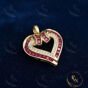 May include: A gold heart-shaped pendant with a ruby and diamond design. The pendant features a heart outline with channel-set rubies and a row of diamonds. The pendant is on a dark blue background.