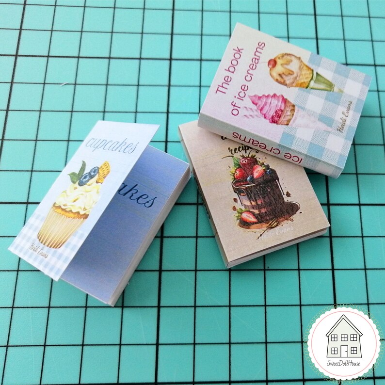 May include: Three miniature cookbooks with colorful covers featuring cupcakes, ice cream, and a chocolate cake. The books are titled "Cupcakes", "The Book of Ice Creams", and "Ice Creams".