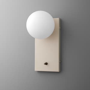 May include: A modern wall sconce featuring a round, white globe light fixture. The light is mounted on a rectangular, cream-colored backplate with a small, round switch. The design is minimalist and contemporary.