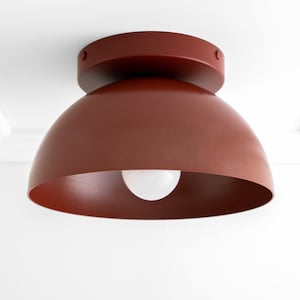 May include: A red dome-shaped ceiling light fixture with a white light bulb.