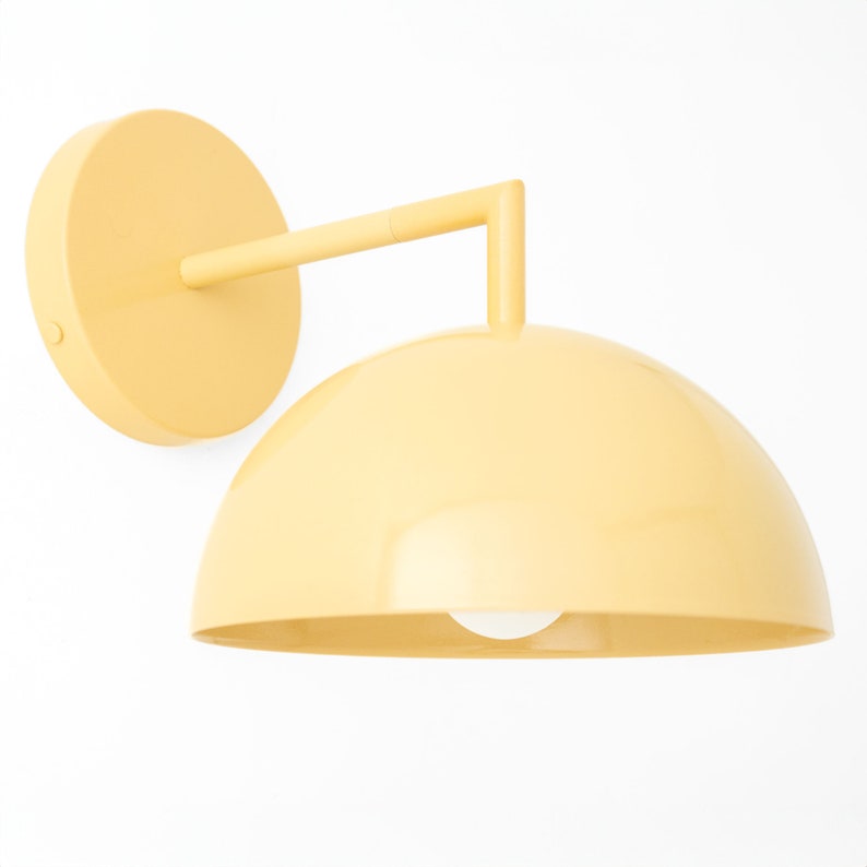 Puede incluir: Una l&aacute;mpara de pared amarilla con una pantalla en forma de c&uacute;pula. La l&aacute;mpara tiene un dise&ntilde;o simple y moderno.