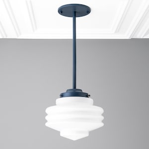 May include: A navy blue pendant light fixture with a white, ribbed glass shade. The light has a circular ceiling mount and a long, straight rod. The shade is a unique shape, wider in the middle and tapering at both ends.