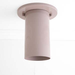 May include: A light pink ceiling light fitting with a cylindrical shade and a round base.