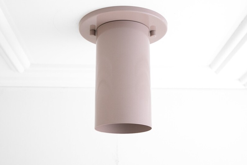 May include: A light pink ceiling light fitting with a cylindrical shade and a round base.