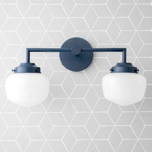 May include: A dark blue bathroom vanity light fixture with two frosted glass globes. The fixture has a round backplate and a straight arm connecting the two globes.
