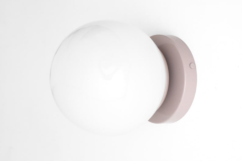 Peut inclure: Un luminaire globe blanc avec une base ronde de couleur brun clair. Le luminaire a un petit bouton rond sur le c&ocirc;t&eacute; de la base.